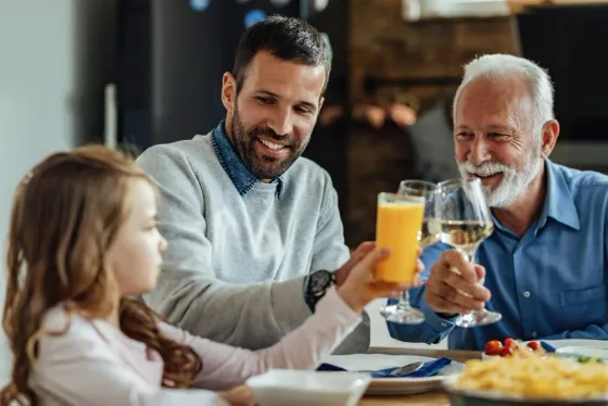 Família reunida brindando com suco natural durante uma refeição